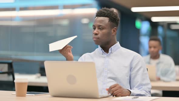 African Businessman with Laptop Flying Paper Plane