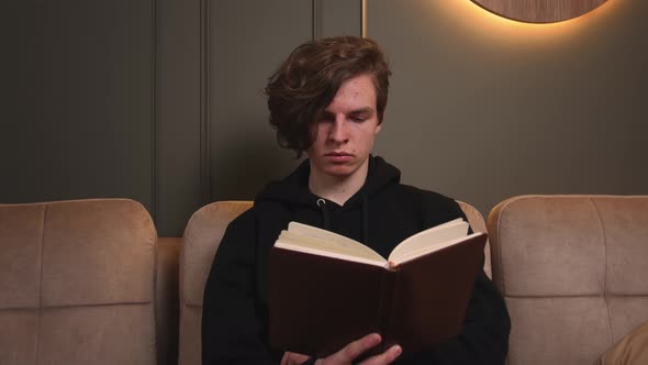 Portrait of Caucasian Man Reading Book Sitting on Couch at Home