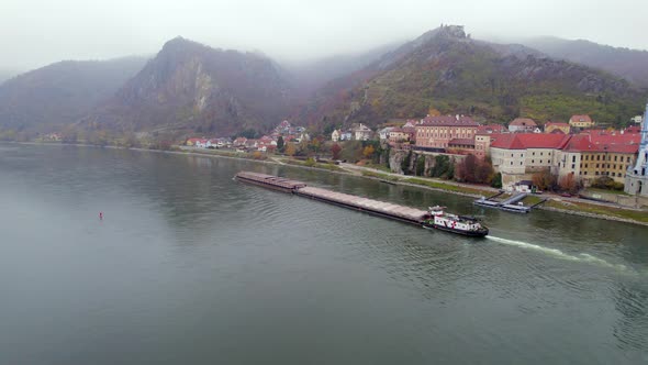 Cargo Pusher Boat on a River Transporting Cargo and Goods Past a Town