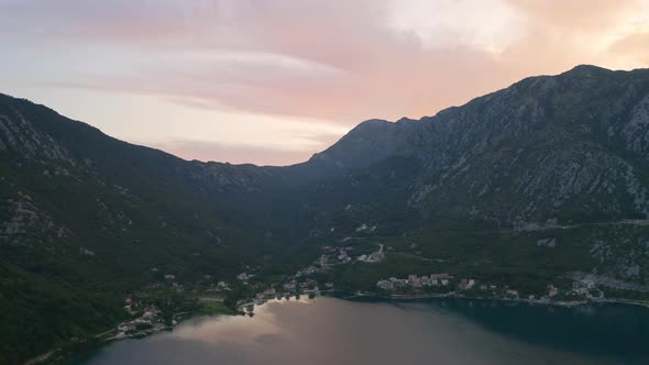 A coastal town on the shore of the bay of Kotor in Montenegro surrounded by high mountains, the Sun