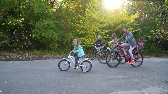 Family biking in park in bright sunshine