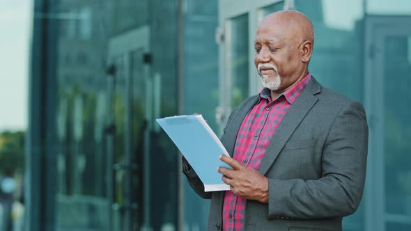 Elderly Serious Concentrated Businessman Architect or Artist Standing Outdoors Holding Paper