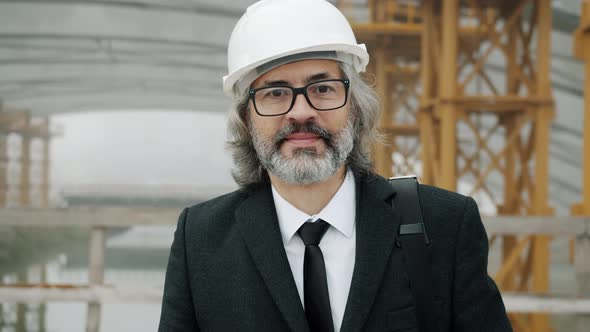 Slow Motion Portrait of Successful Mature Man Architect Wearing Safety Helmet Standing in