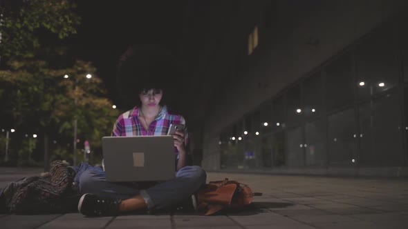 Smiling woman using laptop and smartphone for a video chat at night
