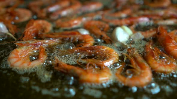 frying prawns in paellon with garlic and virgin olive oil during the preparation of fideua