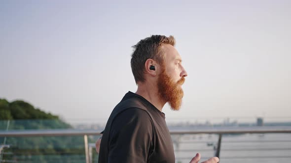 Man with Long Beard Runs on Red Bike Track on Footbridge