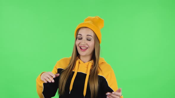 Portrait of Modern Girl in Yellow Hat Is Clapping Her Hands with Dissatisfaction. Green Screen