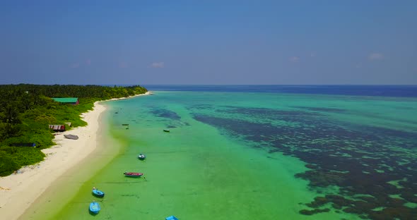 Wide angle above copy space shot of a white paradise beach and blue ocean background in 4K