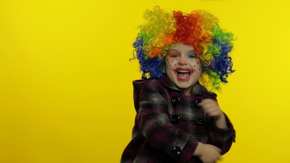 Little Child Girl Clown in Rainbow Wig Making Silly Faces. Having Fun, Smiling, Dancing. Halloween