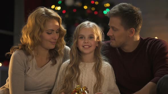 Family Showing Christmas Present to Camera, Preparations Before Holiday Wishlist