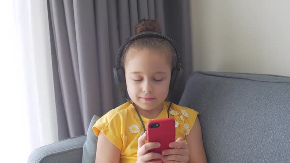 Closeup Portrait of a Small Curlyhaired Girl in Red Headphones