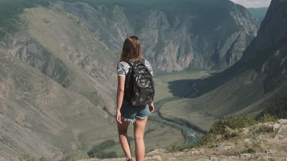 A Female Traveler with a Rucksack Climbs To the Top of the Mountain and Raises His Hands Up, Feeling