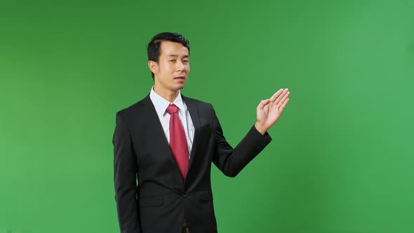 Asian Businessman Pointing On Something And Talking On A Green Screen, Chroma Key