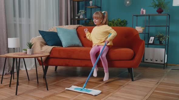 Child Girl Kid Washes Floors with a Mop in Domestic Living Room Dancing Singing in Positive Mood