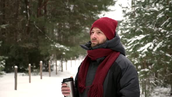 Young Man in Winter Forest Walking Drinking Hot Coffee