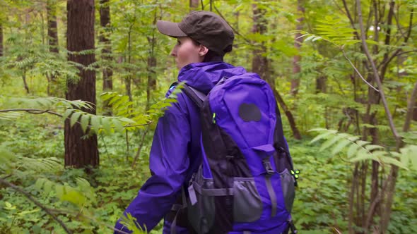 Girl with a Backpack Is in the Green Forest