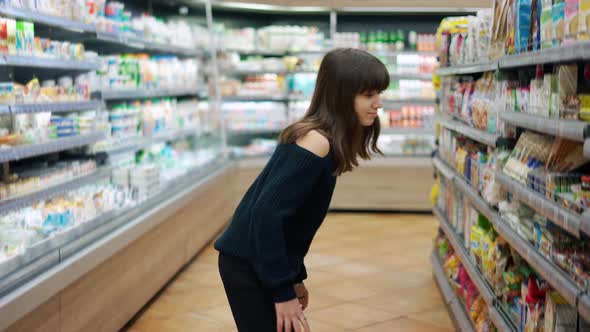 Cheerful Teenager in the Supermarket Taking Sweets From the Shelf