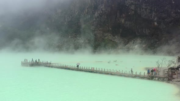 aerial drone of a green toxic sulfur lake inside a volcano called Kawah Putih with fumes and gasses