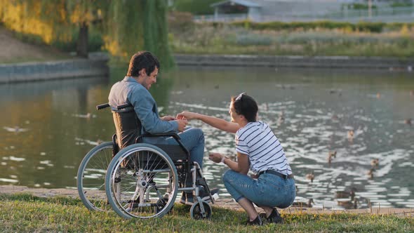 Man in a Wheelchair and Nurse Feeding Ducks