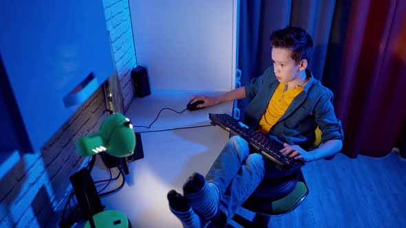 Teen boy is enjoying computer games at home