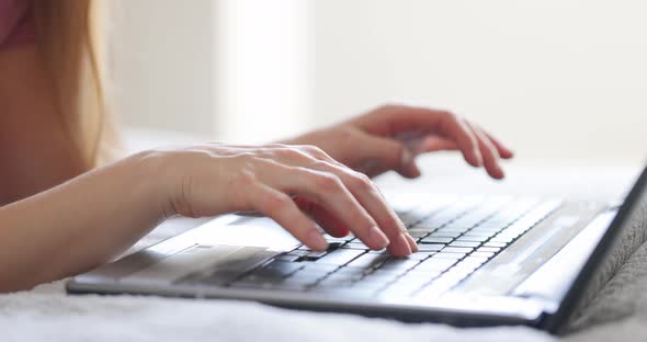 Female Hands Typing on Laptop Keyboard on Bed at Bedroom Close Up