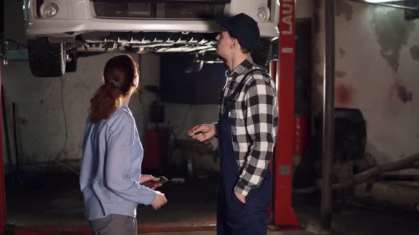 Worker Helps Feminine Client with Vehicle and Checks Technical Condition Auto in Car Service