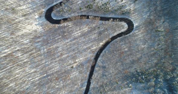 Curvy Country Road Through Winter Woodland From Above in 4K