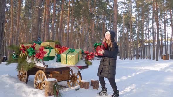 Cheerful Girl Throw Up Red Gift Box in Winter Snowy Forest