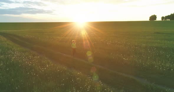 Sporty Child Runs Through a Green Wheat Field