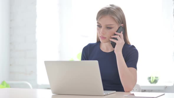 Woman Talking on Phone While Using Laptop