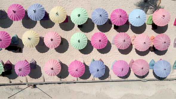 Aerial dolly top down of multicolor umbrellas on empty beach during covid19 pandemic in Asia.