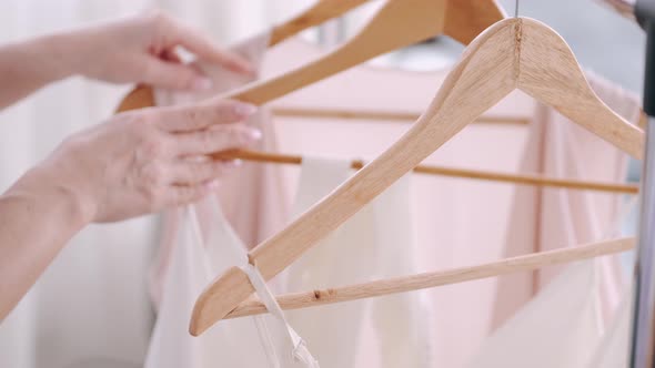 A Female Professional Tailor Is Appreciating a Dress on a Hanger