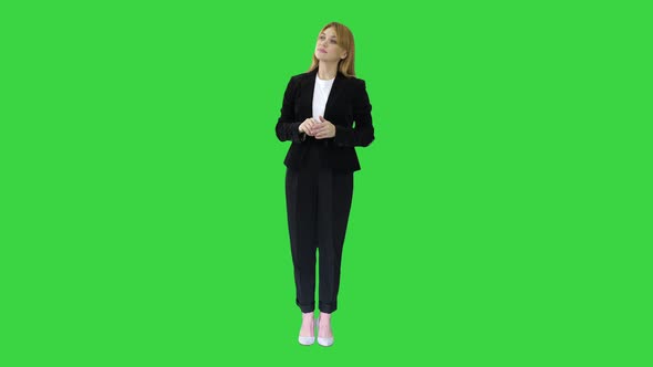 Young Business Woman Presenting Something Pointing at Virtual Objects To Her Sides on a Green Screen