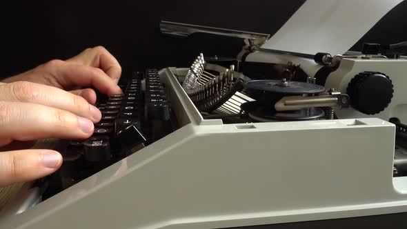 The man is typing on a retro typewriter.