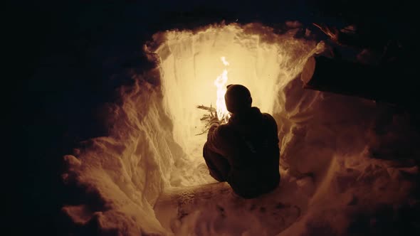 Man Surviving by a fire in a Snow Storm. Digging down in the snow.