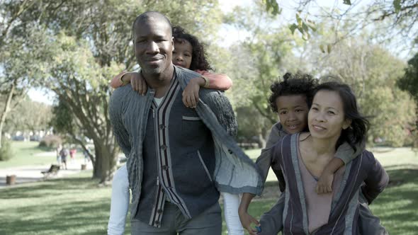 Young Asian Mother, African American Father Holding Kids on Back