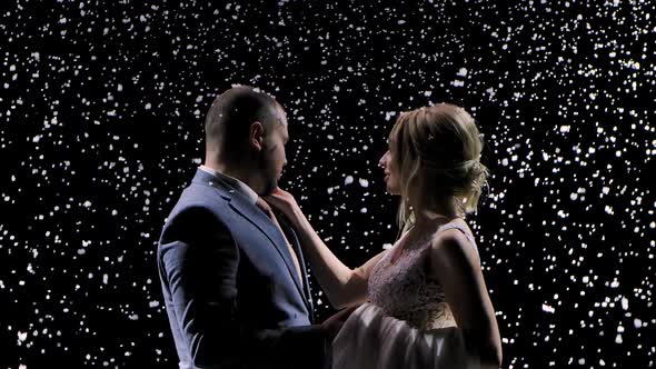Couple of Newlyweds in Love on the Background of Falling Snow. The Woman Gently Strokes Her Man's