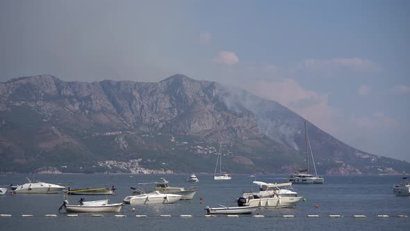 Sailboats Float in the Sea Against the Background of Smoke From Fires in Budva