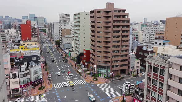 Tokyo city skyline and busy traffic on a cloudy grey day. Pan shot from high up. Gimbal.