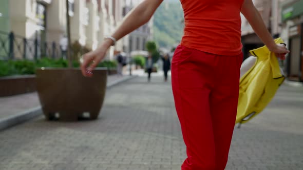 a Woman's Body in Red Clothes and with a Yellow Jacket in Hand Walks Jumps and Turns on a City