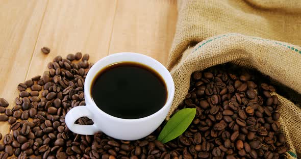 Coffee cup with coffee beans and leaf