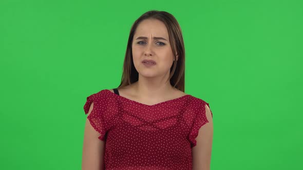 Portrait of Tender Girl in Red Dress Is Upset and Sighing. Green Screen