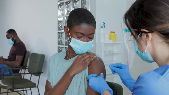 Female doctor giving injection to black female patient