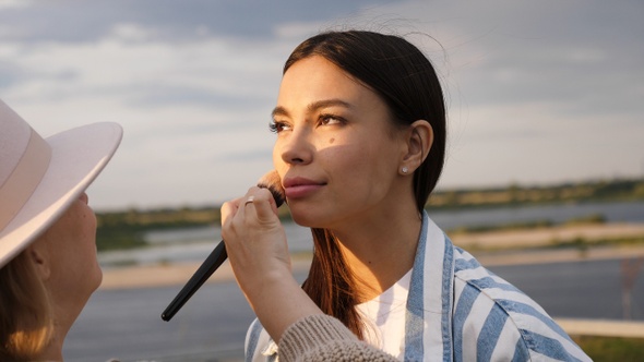 Visagiste helping Beautiful model to put on make up