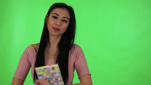 Young Attractive Asian Woman Holds Book in Hands and Smiles To Camera - Green Screen Studio