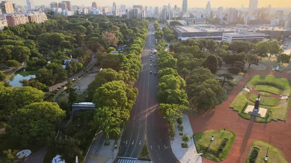 Panning left of a square and natural reservoir park with busy avenue leading to Palermo buildings in