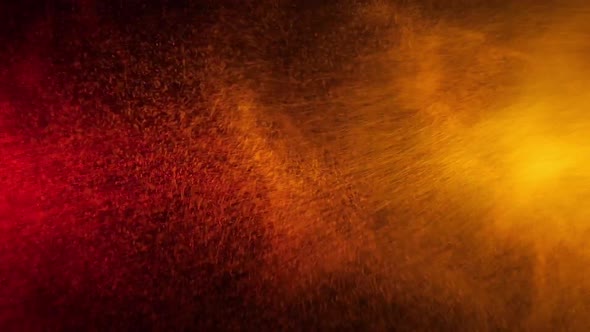 Red and Yellow Water Spray Mixed on a Black Background. Slow Motion