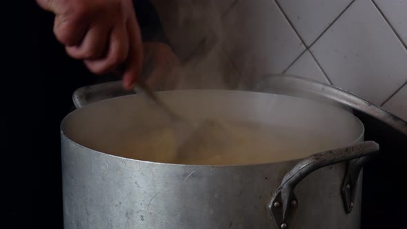 A Volunteer Cook Stirs Porridge in a Large Pot While Preparing Food for the Homeless