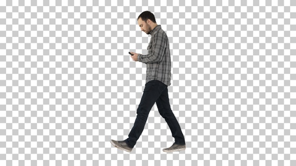 Full Length Portrait Side View. Young Smart Casual Man Walking and Reading Message on Cell Phone