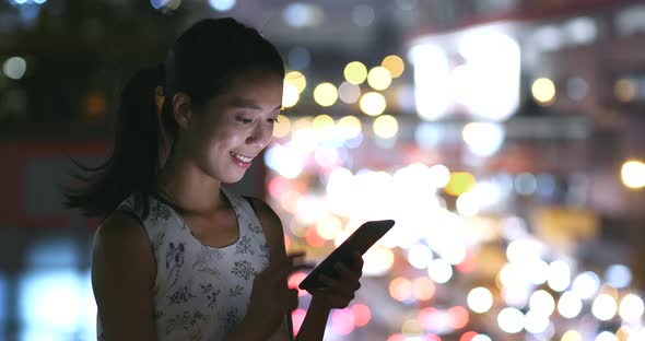 Woman use of smart phone in city at night 